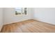 Bright bedroom with light wood-look flooring, white walls, and large window overlooking an open view at 45933 Wood Thrush Ave, Bennett, CO 80102