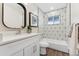 Updated bathroom featuring geometric tile accent wall, white vanity, and modern fixtures at 1227 Yost St, Aurora, CO 80011