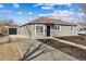 Charming single-story home with a long driveway and detached garage under a partly cloudy blue sky at 1227 Yost St, Aurora, CO 80011