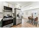 Modern kitchen featuring stainless steel appliances, white upper cabinets, and stylish tile backsplash, with an adjacent dining area at 1227 Yost St, Aurora, CO 80011