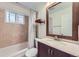 Bathroom featuring wood vanity, tiled shower with tub and framed mirror at 951 Tennyson St, Denver, CO 80204