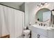 Well-lit bathroom featuring a shiplap accent wall, round mirror, modern vanity and shower at 5490 Suffolk Ave, Castle Rock, CO 80104