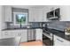 Modern kitchen features white cabinets, stainless steel appliances, gray subway tile backsplash, and a window overlooking the yard at 8836 Marathon Rd, Longmont, CO 80503