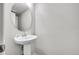 Stylish half bathroom featuring a pedestal sink, oval mirror, and modern fixtures in a neutral color scheme at 5023 Goshawk Ct, Brighton, CO 80601