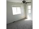 This bedroom features neutral carpet, two bright windows, and a ceiling fan at 5023 Goshawk Ct, Brighton, CO 80601