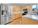 Bright kitchen with stainless steel refrigerator, wood cabinets, modern appliances, and durable countertops at 5023 Goshawk Ct, Brighton, CO 80601