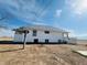 View of the back of the white house with a metal roof, showing a deck and open space at 17362 County Road 29, Platteville, CO 80651
