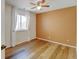 Bright bedroom featuring hardwood floors, large window, and a ceiling fan providing a comfortable and inviting space at 11358 W 85Th Pl # E, Arvada, CO 80005