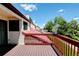 A wooden deck with red railing offering views of neighborhood greenery and rooftops at 11358 W 85Th Pl # E, Arvada, CO 80005