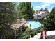 Community pool area with lounge chairs surrounded by lush green trees and a building with a red tile roof at 11358 W 85Th Pl # E, Arvada, CO 80005