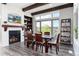 Dining area with a white stone fireplace, wood beam ceiling, large windows with backyard views, and wood furniture at 5409 Sedona Dr, Parker, CO 80134