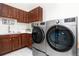 Well-equipped laundry room featuring modern washer/dryer units, cabinetry, sink, and stylish tile flooring at 5409 Sedona Dr, Parker, CO 80134
