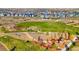 A scenic aerial view of a large community park with playground and lush greenery, surrounded by colorful homes at 6393 N Malaya St, Aurora, CO 80019