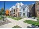 Modern townhome with a mix of white siding and brick, complemented by a well-maintained green lawn and sidewalk at 2550 Lawrence St # 106, Denver, CO 80205