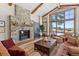 Comfortable living room with stone fireplace, wood beams, and expansive windows offering stunning mountain vistas at 6169 Flat Creek Dr, Evergreen, CO 80439
