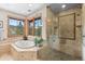 Luxurious bathroom with a soaking tub, glass-enclosed shower, and large windows offering natural light at 6169 Flat Creek Dr, Evergreen, CO 80439