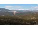 Scenic mountain view showcasing rolling hills, dense forest, and distant snow-capped peaks under a blue sky at 6169 Flat Creek Dr, Evergreen, CO 80439