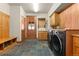 A modern mudroom with a built-in bench, laundry area and exterior door at 6169 Flat Creek Dr, Evergreen, CO 80439