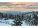 Scenic mountain view with snow-covered trees and soft, colorful sky at dusk, framed by a rustic wooden fence at 6169 Flat Creek Dr, Evergreen, CO 80439
