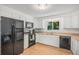 A bright kitchen featuring white cabinetry, modern black appliances, and a stainless steel sink under a window at 1641 Biscay Cir, Aurora, CO 80011