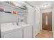Laundry room featuring a washer, dryer, and storage shelves, with a view of the front entry door at 1641 Biscay Cir, Aurora, CO 80011
