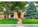 Charming stucco home with a beautiful lawn, mature trees, and a quaint outdoor seating area at 2411 S Milwaukee St, Denver, CO 80210