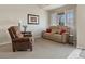 Comfortable living room featuring a reclining sofa, plush armchair, and bright window at 512 Cardens Pl, Erie, CO 80516