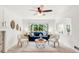 Bright living room features a blue sofa, ceiling fan, neutral chairs, and an abundance of natural light from large picture window at 19428 E Crestridge Cir, Centennial, CO 80015