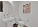 Charming half bathroom featuring a pedestal sink, round mirror, and decor at 16347 E 111Th Dr, Commerce City, CO 80022