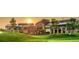 Beautiful sunset view of clubhouse featuring stone and metal architecture and manicured lawn at 23590 E Jamison Pl, Aurora, CO 80016
