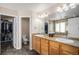 Bathroom featuring double sinks with wood cabinets and a glass shower with stone flooring at 7004 S Addison Ct, Aurora, CO 80016