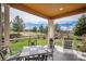 Covered patio with outdoor dining and rocking chair area overlooks the lush backyard and green space at 7004 S Addison Ct, Aurora, CO 80016