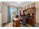 Home office featuring a large desk, wood shelving, and a bright window at 7004 S Addison Ct, Aurora, CO 80016