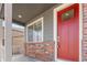 Close-up of a charming front porch with a red door and brick accents at 8388 E 132Nd Pl, Thornton, CO 80602