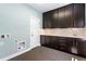 Well-organized laundry room featuring dark wood cabinetry, tile floors, and ample storage space at 16069 Pikes Peak Dr, Broomfield, CO 80023