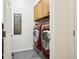 Laundry room featuring a modern, red washer and dryer set with wood cabinets for storage and grey tile flooring at 9139 Flora St, Arvada, CO 80005