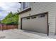 Attached two car garage with a beige door and natural surrounding landscape at 1310 Hoyt St # 6, Lakewood, CO 80215