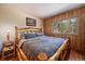 Comfortable bedroom featuring wood-paneled walls and a beautiful view of the surrounding landscape at 28539 Douglas Park Rd, Evergreen, CO 80439