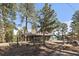 Quaint exterior view of home with fenced yard and mature trees at 28539 Douglas Park Rd, Evergreen, CO 80439