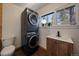 A utility room with stackable washer/dryer and wood paneled vanity at 28539 Douglas Park Rd, Evergreen, CO 80439
