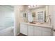 Well-lit bathroom has a double sink, quartz countertop, and tub with tiled shower at 9467 W Plymouth Ave, Littleton, CO 80128
