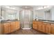 Bathroom boasts dual sinks, wooden cabinets, corner shower, and neutral decor at 9467 W Plymouth Ave, Littleton, CO 80128