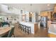 Open concept kitchen with island seating, stainless refrigerator, and adjoined open living spaces at 9467 W Plymouth Ave, Littleton, CO 80128