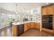 Sunlit kitchen with quartz countertops, wood cabinets, stainless appliances, and a view of the living area at 9467 W Plymouth Ave, Littleton, CO 80128