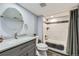 Modern bathroom features a vanity with stone countertop, updated shower and a large round mirror at 15645 E Floyd Ave, Aurora, CO 80013