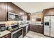 Well lit kitchen with stainless appliances, wood cabinets, and vinyl flooring at 15645 E Floyd Ave, Aurora, CO 80013