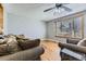 A comfy living room with ceiling fan, hardwood floors, and large window with wooden trim at 15645 E Floyd Ave, Aurora, CO 80013