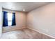 Empty bedroom boasts neutral walls, carpet, and a window with stylish blue curtains at 5152 Bittercress Rd, Brighton, CO 80640