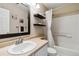 Bright bathroom featuring a single sink vanity, tile surround bathtub, and stylish floating shelves at 9378 Longstone Dr, Parker, CO 80134