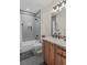 Modern bathroom with gray tiled shower and floors, modern lighting, and wood vanity with solid surface countertops at 1845 W 33Rd Ave, Denver, CO 80211